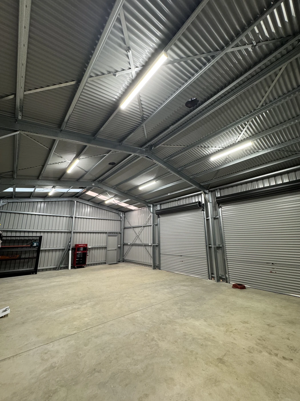 Commercial lighting installed beneath the metal roof of a workshop